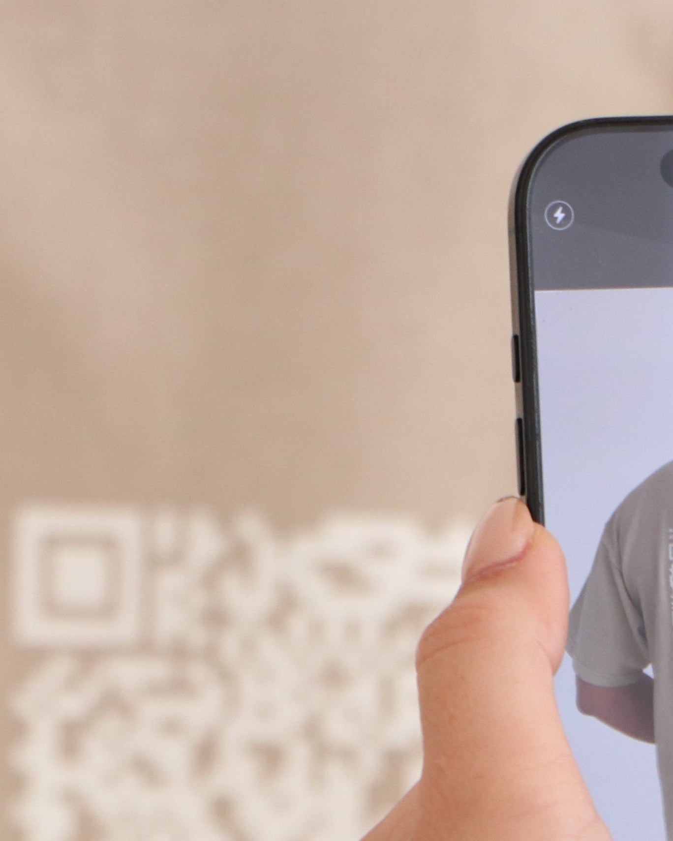 Person taking a photo of a shirt with a QR code using a smartphone.