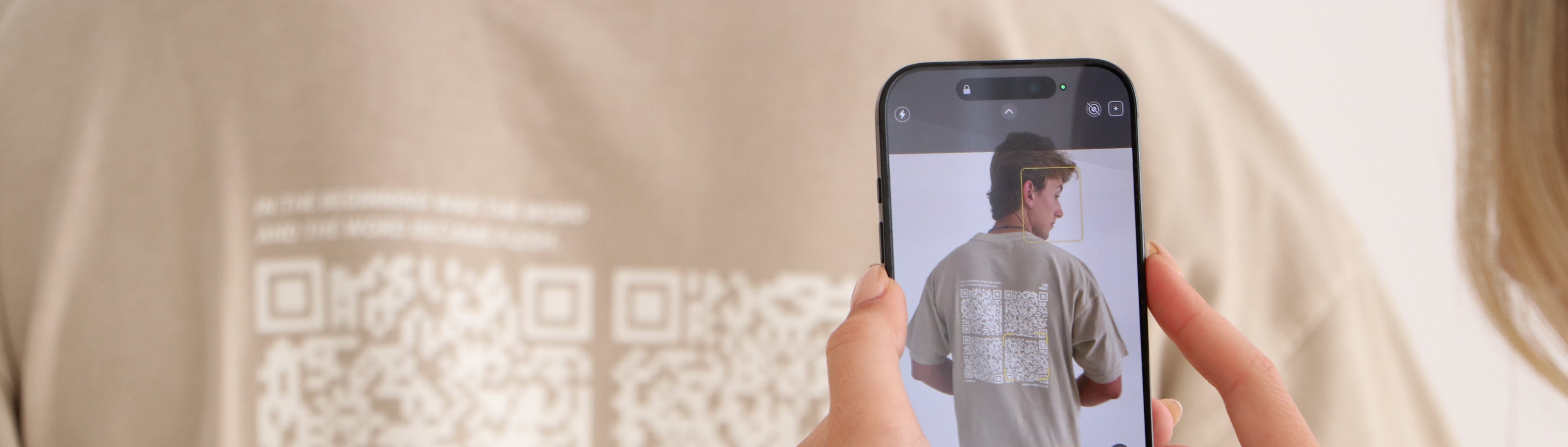 Person taking a photo of a shirt with a QR code using a smartphone.